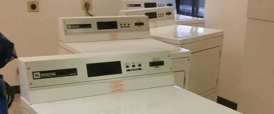 dryers from a laundromat pulled away from the wall to allow for dryer vent cleaning